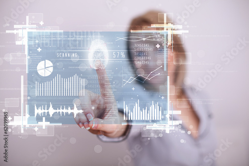 Photo: Young businesswoman pressing modern technology panel with finger Young businesswoman pressing modern technology panel with finger