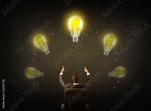 Photo: Businessman sitting with lightbulbs over his head Businessman sitting with lightbulbs over his head
