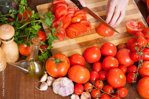 Photo: Closeup of female hands slicing tomatoes Closeup of female hands slicing tomatoes