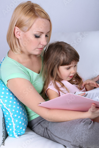 Photo: Pretty little girl reading book with mother Pretty little girl reading book with mother