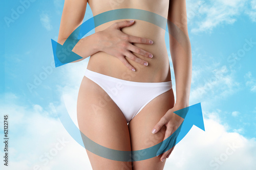 Photo: Woman's hands on stomach on sky background wellness concept Woman's hands on stomach on sky background wellness concept