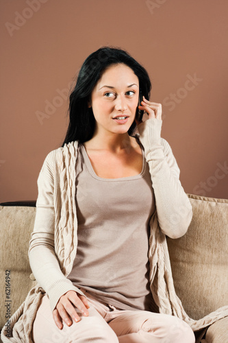 Photo: Woman sitting on the sofa and talking on the phone Woman sitting on the sofa and talking on the phone