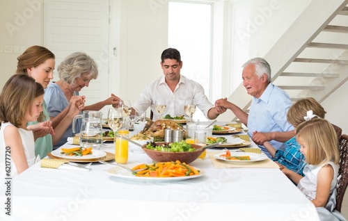 Photo: Family praying together before meal at dining table Family praying together before meal at dining table