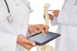Mid section of doctors with digital table and skeleton model Mid section of doctors with digital table and skeleton model
