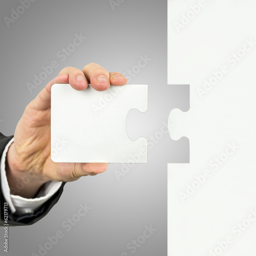 Photo: Businessman holding the missing piece of a puzzle Businessman holding the missing piece of a puzzle