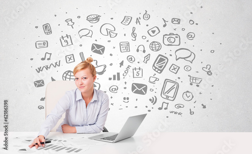 Photo: Young businesswoman with all kind of hand-drawn media icons in b Young businesswoman with all kind of hand-drawn media icons in b
