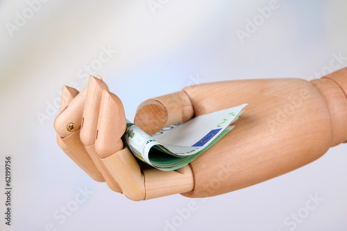 Photo: Money in wooden hand, on light background Money in wooden hand, on light background