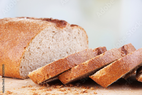 Photo: Sliced bread on wooden board on bright background Sliced bread on wooden board on bright background