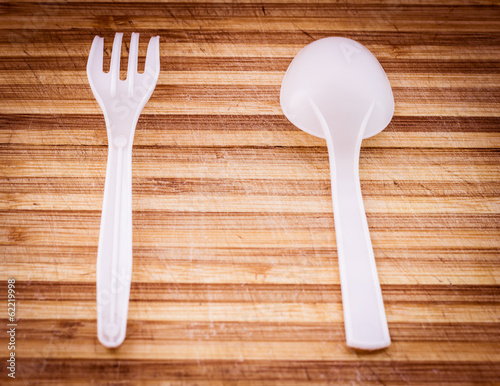 Photo: Plastic knife and fork on old wooden surface. Selective focus. Plastic knife and fork on old wooden surface. Selective focus.