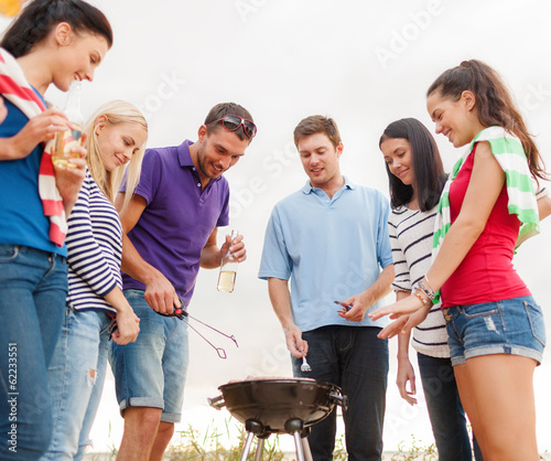 Photo: group of friends making barbecue on the beach group of friends making barbecue on the beach