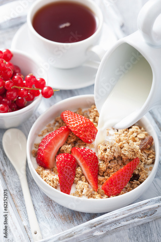 Photo: milk pouring over granola with strawberry for breakfast milk pouring over granola with strawberry for breakfast