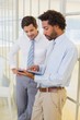 Businessmen looking at digital tablet in office Businessmen looking at digital tablet in office
