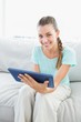 Smiling woman sitting on couch using tablet pc Smiling woman sitting on couch using tablet pc
