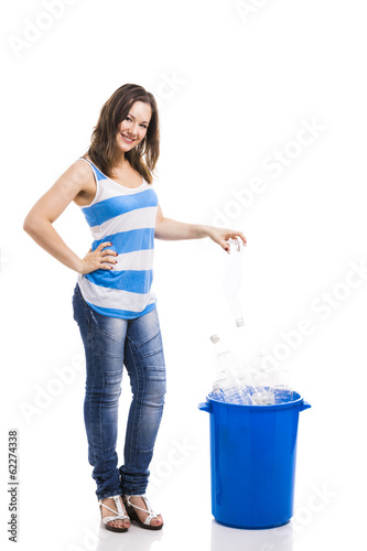 Photo: Beautiful young woman putting a bottle on a recycle contentor Beautiful young woman putting a bottle on a recycle contentor