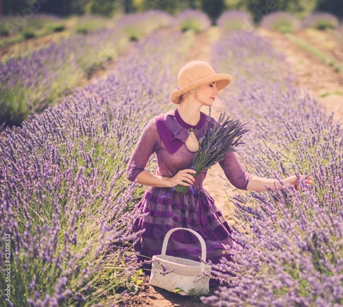 Photo: Woman in purple dress and hat with basket in lavender field Woman in purple dress and hat with basket in lavender field