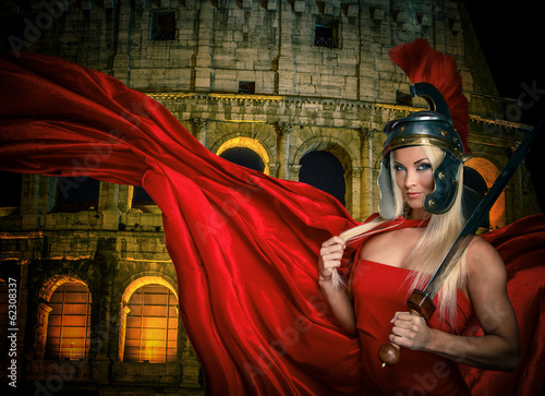 Photo: Fit blonde gladiatrix and Colossseum on the background Fit blonde gladiatrix and Colossseum on the background