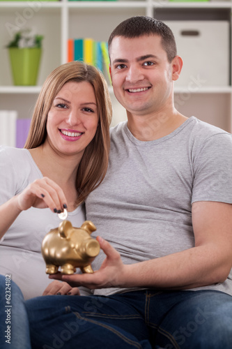 Photo: Smiling couple putting coin Smiling couple putting coin