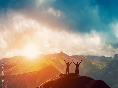 Photo: Happy couple together on the peak of a mountain at sunset Happy couple together on the peak of a mountain at sunset