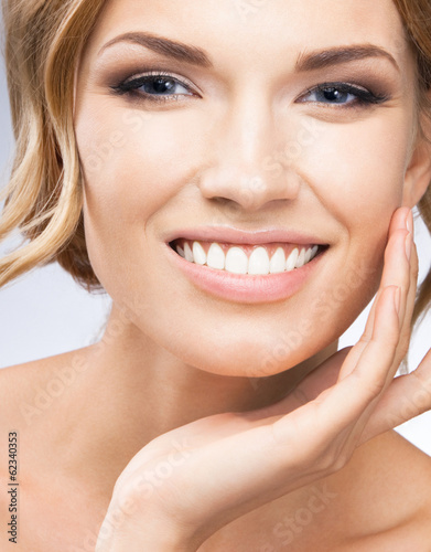 Photo: Woman touching skin or applying cream, on grey Woman touching skin or applying cream, on grey