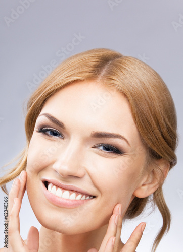 Photo: Woman touching skin or applying cream, on grey Woman touching skin or applying cream, on grey