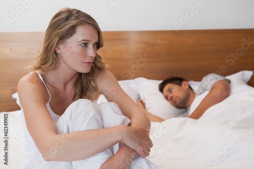 Photo: Sad woman with man sleeping in background Sad woman with man sleeping in background