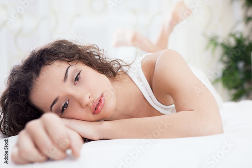 Photo: unhappy young woman lying in a bed unhappy young woman lying in a bed