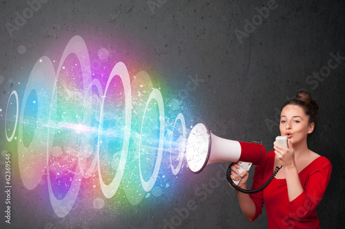 Photo: Young girl yells into a loudspeaker and colorful energy beam com Young girl yells into a loudspeaker and colorful energy beam com