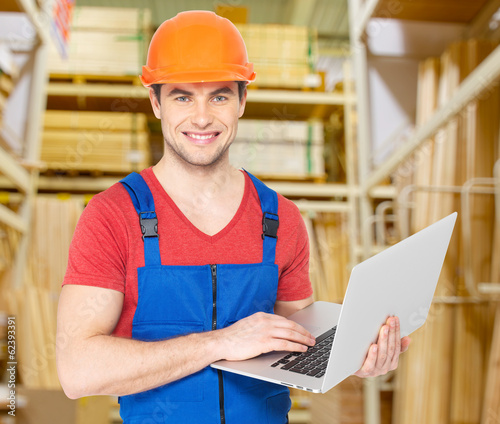 Photo: Portrait of handyman with laptop working warehouse Portrait of handyman with laptop working warehouse