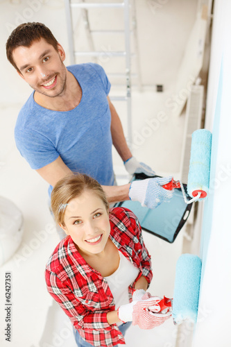 Photo: smiling couple painting wall at home smiling couple painting wall at home