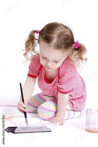 Photo: Funny little girl with ponytails drawing with waterolors Funny little girl with ponytails drawing with waterolors