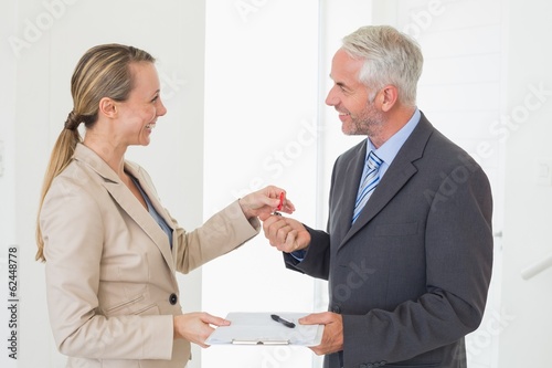 Photo: Smiling estate agent giving house key to happy customer Smiling estate agent giving house key to happy customer