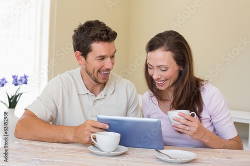 Photo: Couple using digital tablet while having coffee Couple using digital tablet while having coffee
