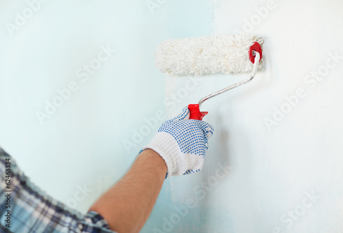 Photo: close up of male in gloves painting wall close up of male in gloves painting wall