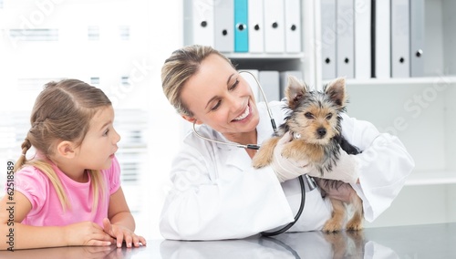 Photo: Veterinarian examining puppy with girl Veterinarian examining puppy with girl
