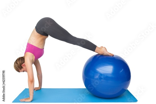 Photo: Side view of a fit young woman stretching on fitness ball Side view of a fit young woman stretching on fitness ball