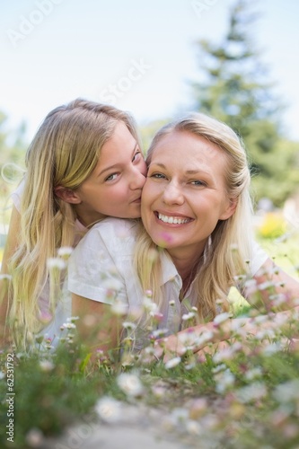 Photo: Girl kissing mother while lying in park Girl kissing mother while lying in park