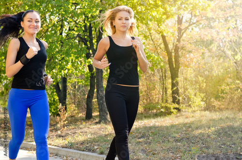 Photo: Two female friends jogging together in a park Two female friends jogging together in a park