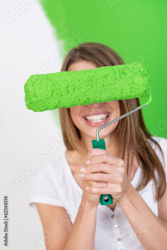 Photo: lachende frau versteckt sich hinter farbrolle lachende frau versteckt sich hinter farbrolle