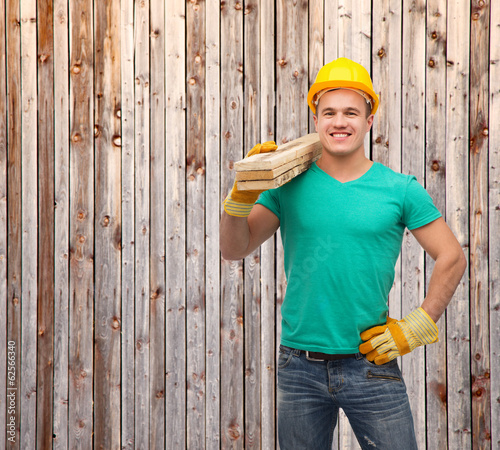 Photo: smiling manual worker in helmet with wooden boards smiling manual worker in helmet with wooden boards