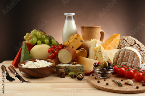 Photo: Tasty dairy products on wooden table, on dark background Tasty dairy products on wooden table, on dark background