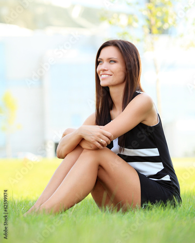 Photo: young smiling business woman outdoors sitting on the grass. young smiling business woman outdoors sitting on the grass.