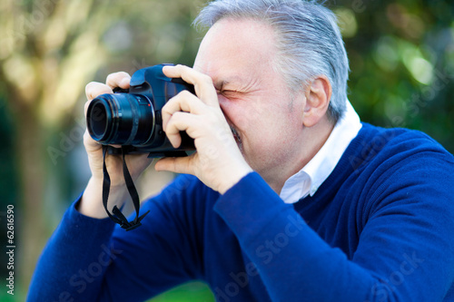 Photo: Enthusiastic photographer taking a photo outdoor. Enthusiastic photographer taking a photo outdoor.