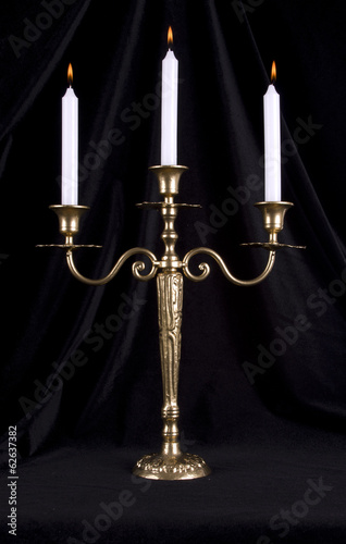 Photo: Vintage brass candelabrum with three burning candles Vintage brass candelabrum with three burning candles