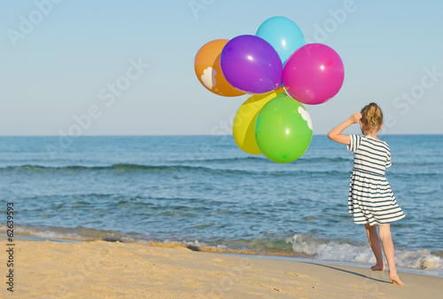Photo: Little girl running with colorful balloons. Little girl running with colorful balloons.