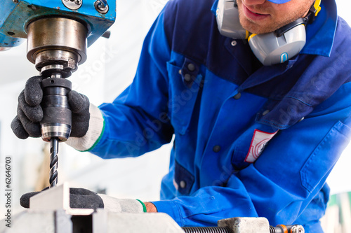 Photo: Handwerker bohrt mit Bohrmaschine in Fabrik Handwerker bohrt mit Bohrmaschine in Fabrik
