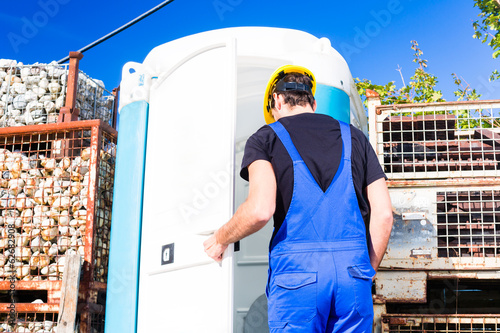Photo: Bauarbeiter benutzt mobile Toilette einer Baustelle Bauarbeiter benutzt mobile Toilette einer Baustelle