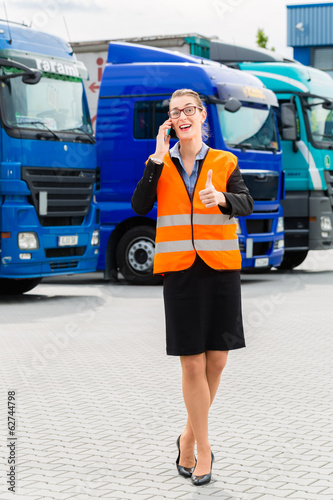 Photo: Spediteurin vor Lastwagen und LKW auf Depot Spediteurin vor Lastwagen und LKW auf Depot