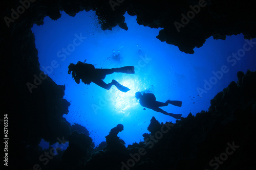  Scuba Divers swim over underwater cave