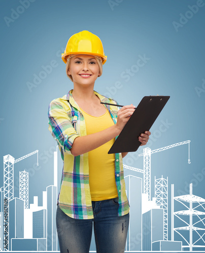 Photo: smiling woman in helmet with clipboard smiling woman in helmet with clipboard