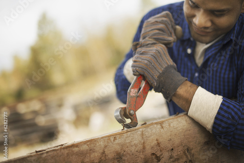 Foto: A man working in a reclaimed timber yard. Using a tool to remove metals from a reclaimed piece of timber. A man working in a reclaimed timber yard. Using a tool to remove metals from a reclaimed piece of timber.